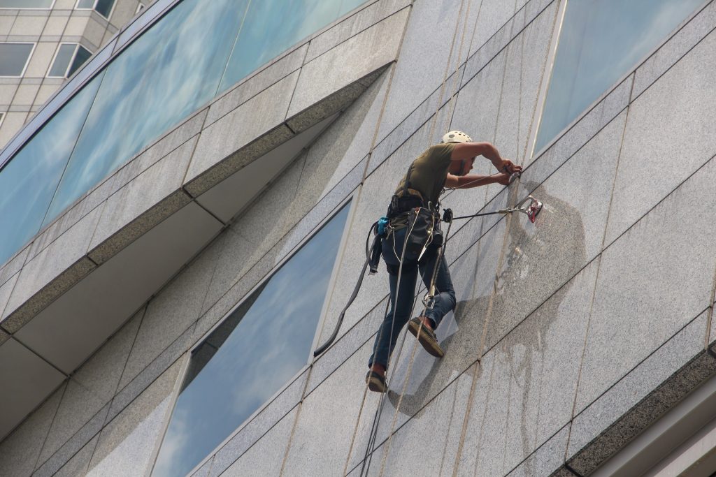 A man suspended from a building cleaning the windows