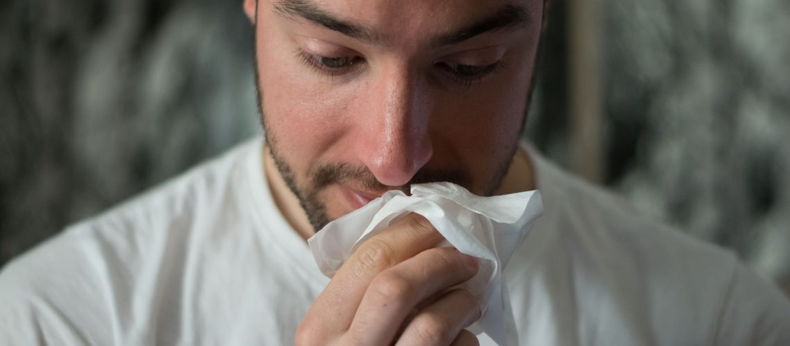 A man with allergies blowing his nose